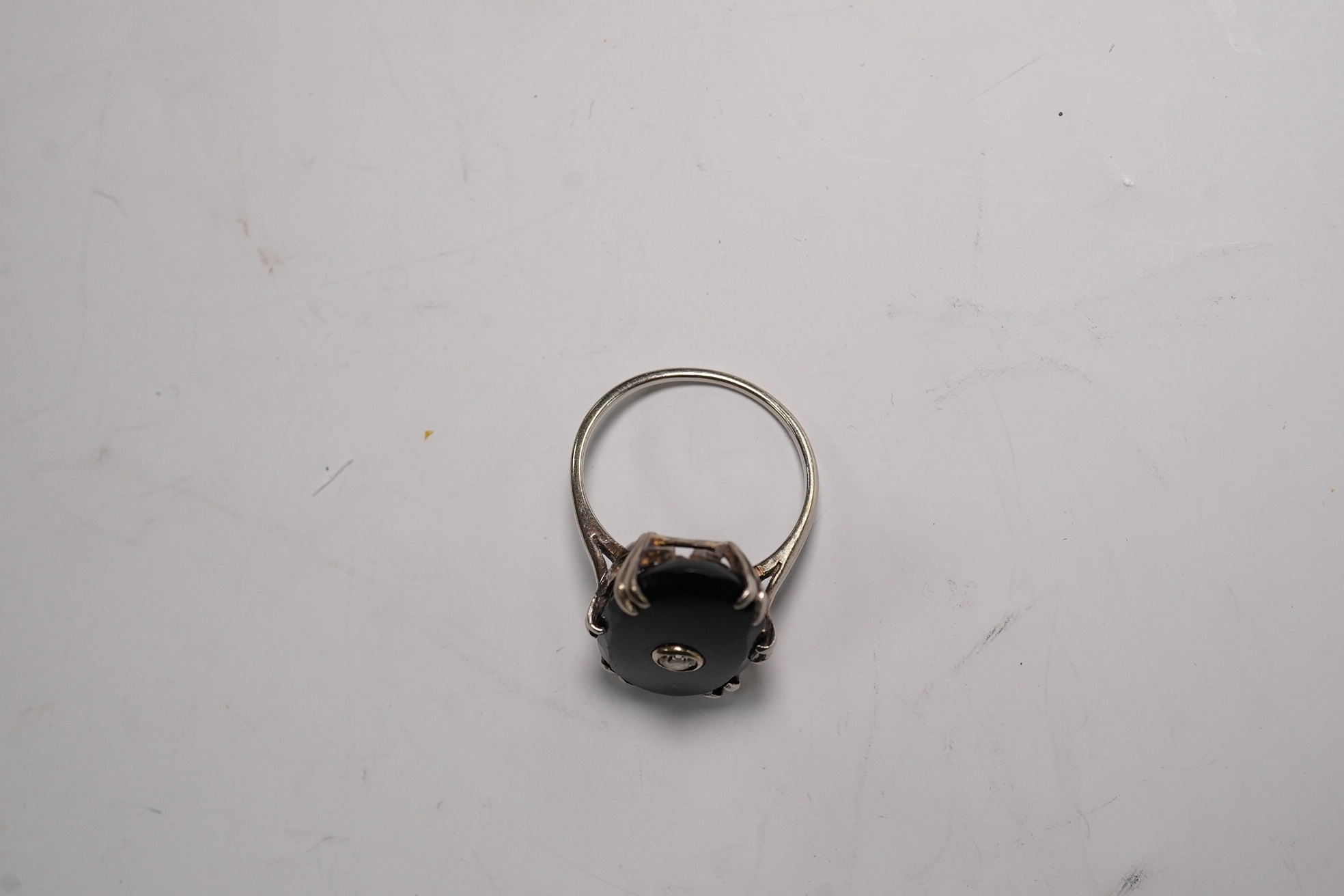 A white metal, black onyx and single stone diamond set oval ring, size M/N, gross weight 3.9 grams. Condition - poor to fair